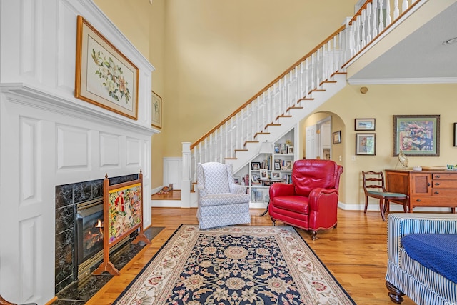 3231 Center Rd, Georgetown, SC 29440 - living room featuring light wood-type flooring, a towering ceiling, arched walkways, a tile fireplace, and stairs