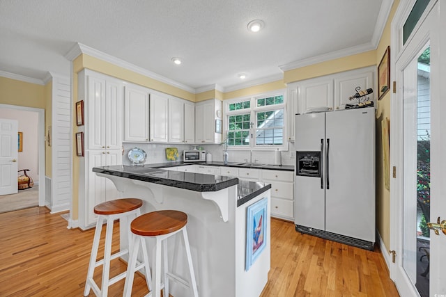 3231 Center Rd, Georgetown, SC 29440 - kitchen with white appliances, a kitchen bar, white cabinetry, decorative backsplash, and light wood finished floors