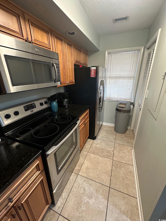 201 Hillside Dr N Unit 111, North Myrtle Beach, SC 29582 - kitchen with stainless steel appliances, a textured ceiling, brown cabinets, light tile patterned floors, and baseboards