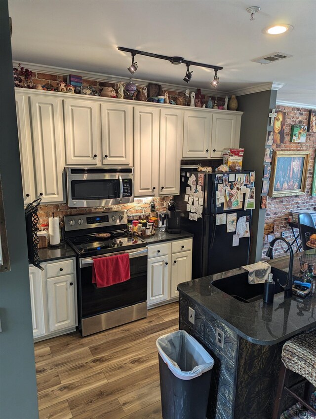 2834 Howard Ave Unit D, Myrtle Beach, SC 29577 - kitchen featuring appliances with stainless steel finishes, a sink, dark countertops, white cabinets, and crown molding
