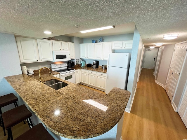 2007 S Ocean Blvd Unit 1506, Myrtle Beach, SC 29577 - kitchen with white appliances, a sink, light wood-type flooring, a peninsula, and dark stone countertops