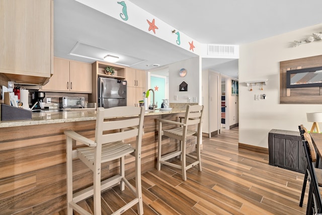 9820 Queensway Blvd Unit 502, Myrtle Beach, SC 29572 - kitchen with freestanding refrigerator, light brown cabinetry, a peninsula, light wood-style flooring, and a breakfast bar area