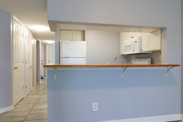 1100 Possum Trot Dr Unit D106, North Myrtle Beach, SC 29582 - kitchen featuring white appliances, a peninsula, white cabinetry, a breakfast bar area, and light tile patterned flooring