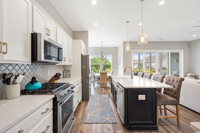 314 Bumble Cir, Murrells Inlet, SC 29576 - kitchen featuring appliances with stainless steel finishes, light wood finished floors, a kitchen bar, open floor plan, and tasteful backsplash