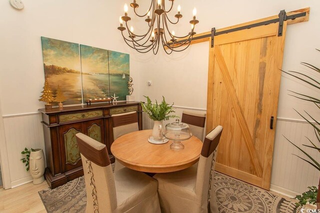 108 Pipers Ln Unit 108, Myrtle Beach, SC 29575 - dining space with a barn door, a chandelier, light wood finished floors, and wainscoting