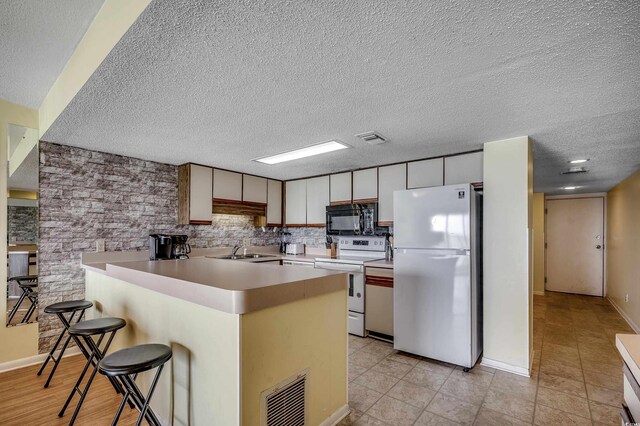 912 N Waccamaw Dr Unit 904, Garden City Beach, SC 29576 - kitchen featuring white appliances, a sink, a peninsula, a textured ceiling, and light countertops
