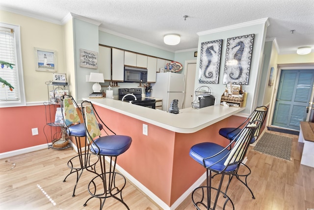 4350 Intercoastal Dr Unit 1101, Little River, SC 29566 - kitchen with black appliances, light wood finished floors, a peninsula, a breakfast bar, and crown molding