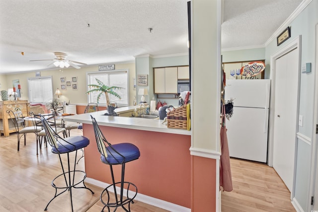 4350 Intercoastal Dr Unit 1101, Little River, SC 29566 - kitchen featuring freestanding refrigerator, a textured ceiling, a breakfast bar area, a sink, and light wood-style flooring