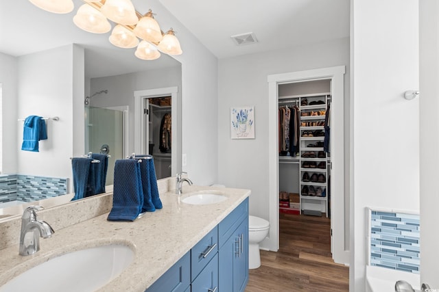 620 Seth Ln, Longs, SC 29568 - full bathroom featuring a walk in closet, double vanity, wood finished floors, a stall shower, and a chandelier