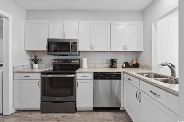800 9th Ave S Unit E-4, North Myrtle Beach, SC 29582 - kitchen featuring appliances with stainless steel finishes, white cabinets, light wood-type flooring, and light stone countertops