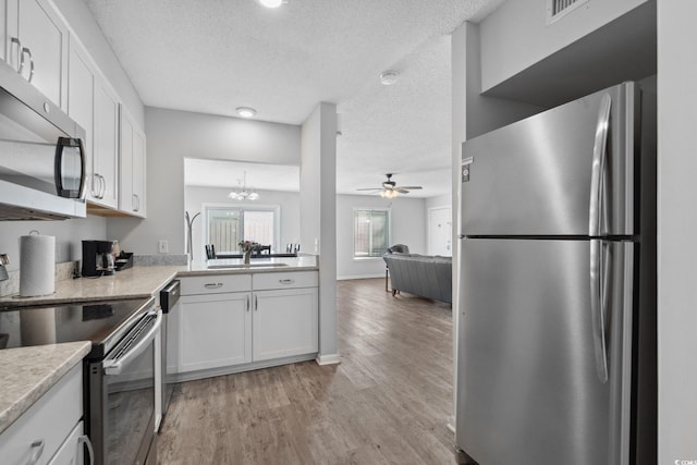 800 9th Ave S Unit E-4, North Myrtle Beach, SC 29582 - kitchen with stainless steel appliances, a textured ceiling, a ceiling fan, light wood-style flooring, and white cabinets