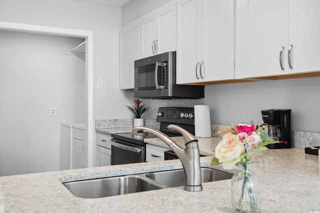 800 9th Ave S Unit E-4, North Myrtle Beach, SC 29582 - kitchen featuring washing machine and dryer, appliances with stainless steel finishes, and white cabinetry