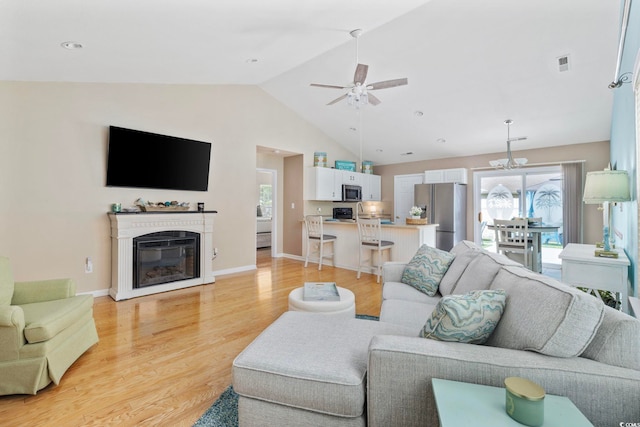 6681 Wisteria Dr, Myrtle Beach, SC 29588 - living room with healthy amount of natural light, light wood-style flooring, lofted ceiling, ceiling fan, and a glass covered fireplace