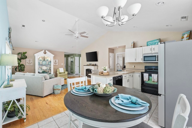 6681 Wisteria Dr, Myrtle Beach, SC 29588 - dining space featuring light tile patterned floors, a chandelier, a fireplace, ceiling fan, and high vaulted ceiling