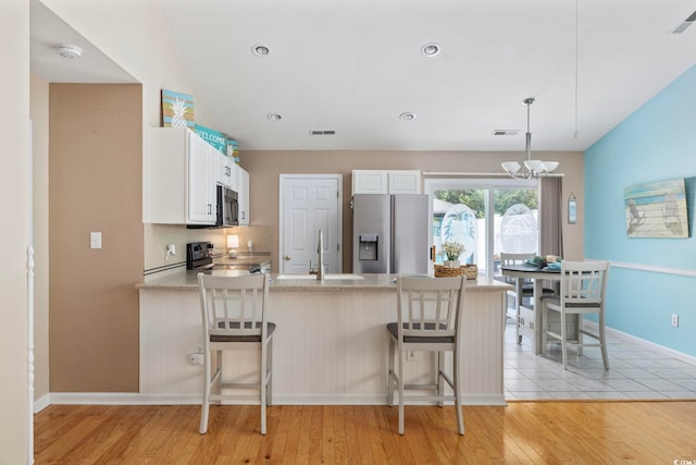 6681 Wisteria Dr, Myrtle Beach, SC 29588 - kitchen featuring stainless steel appliances, a peninsula, a sink, light countertops, and white cabinetry