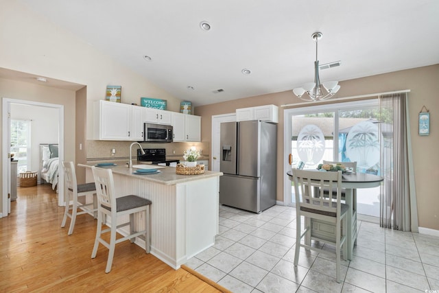 6681 Wisteria Dr, Myrtle Beach, SC 29588 - kitchen with stainless steel appliances, a chandelier, white cabinets, light countertops, and vaulted ceiling
