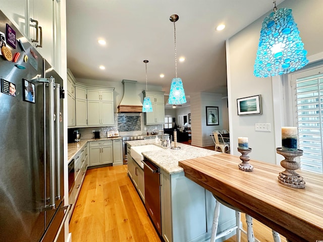 70 Beachwalker Ct, Georgetown, SC 29440 - kitchen with appliances with stainless steel finishes, premium range hood, recessed lighting, light wood-type flooring, and decorative backsplash