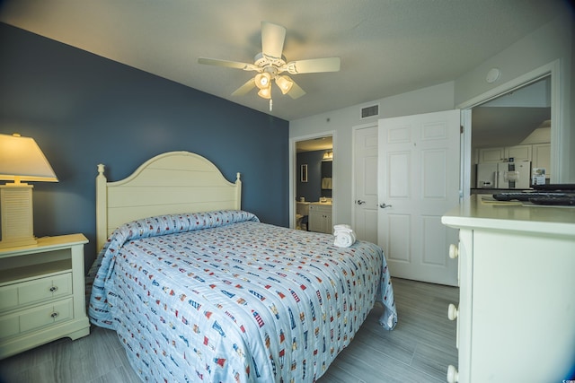 1903 S Ocean Blvd Unit 1110, North Myrtle Beach, SC 29582 - bedroom with stainless steel fridge with ice dispenser, ceiling fan, wood finished floors, and ensuite bath