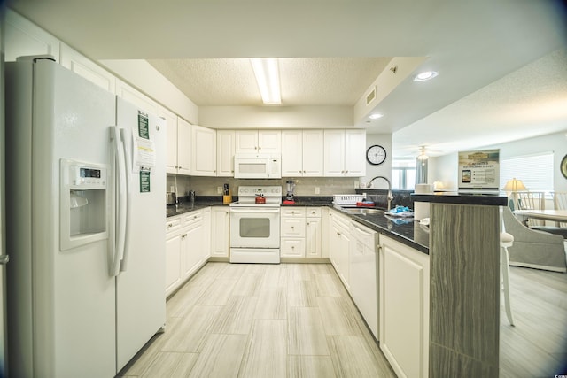 1903 S Ocean Blvd Unit 1110, North Myrtle Beach, SC 29582 - kitchen featuring white appliances, a sink, a peninsula, a kitchen bar, and white cabinetry