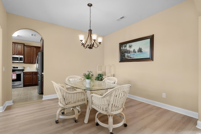 1149 6th Ave S, North Myrtle Beach, SC 29582 - dining space with light wood finished floors, arched walkways, a chandelier, and baseboards