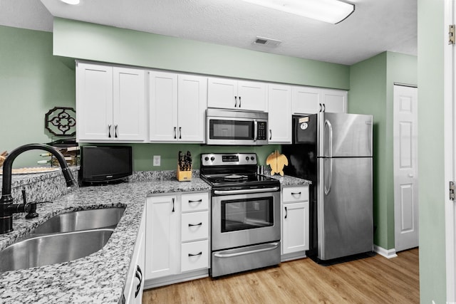 117 Pinehurst Ln Unit 5-J, Pawleys Island, SC 29585 - kitchen featuring stainless steel appliances, a sink, light wood-style floors, and white cabinetry
