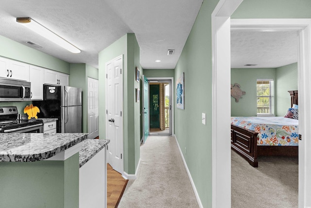 117 Pinehurst Ln Unit 5-J, Pawleys Island, SC 29585 - kitchen with appliances with stainless steel finishes, a textured ceiling, white cabinetry, healthy amount of natural light, and baseboards