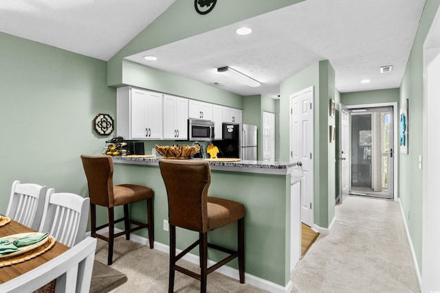 117 Pinehurst Ln Unit 5-J, Pawleys Island, SC 29585 - kitchen featuring appliances with stainless steel finishes, light colored carpet, a peninsula, baseboards, and a kitchen bar