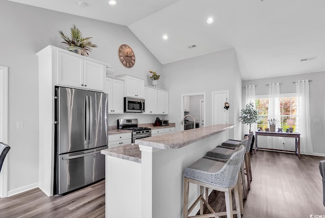 832 Windsor Rose Dr, Conway, SC 29526 - kitchen featuring appliances with stainless steel finishes, light countertops, wood finished floors, an island with sink, and high vaulted ceiling