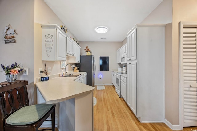 155 Lazy Willow Ln Unit 103, Myrtle Beach, SC 29572 - kitchen with a sink, light countertops, a breakfast bar area, white appliances, and light wood-style flooring