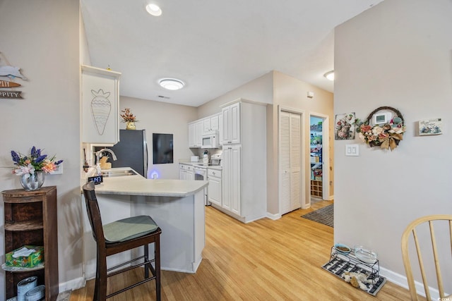 155 Lazy Willow Ln Unit 103, Myrtle Beach, SC 29572 - kitchen with white appliances, a sink, white cabinetry, a breakfast bar area, and light wood-style flooring