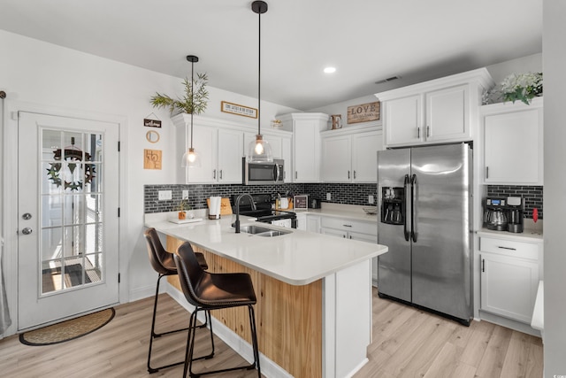 136 Southbury Dr, Myrtle Beach, SC 29588 - kitchen featuring appliances with stainless steel finishes, light wood-type flooring, a peninsula, decorative backsplash, and a kitchen breakfast bar