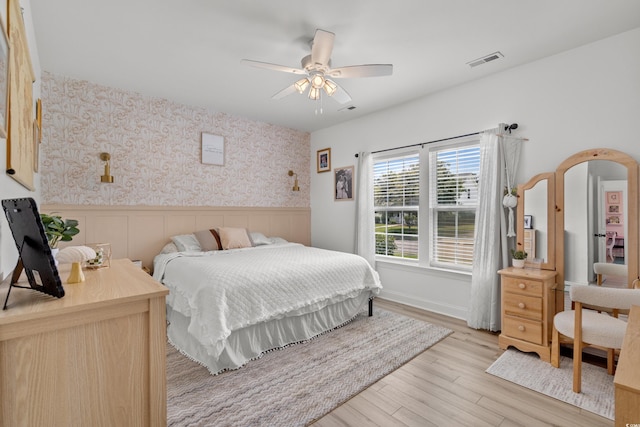 136 Southbury Dr, Myrtle Beach, SC 29588 - bedroom featuring wainscoting, wallpapered walls, light wood-style flooring, and ceiling fan
