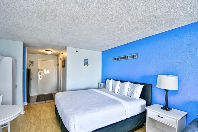 1207 S Ocean Blvd Unit 51012, Myrtle Beach, SC 29577 - bedroom featuring light wood finished floors, a textured ceiling, and freestanding refrigerator