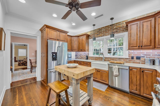 1259 Oatland Lake Rd, Pawleys Island, SC 29585 - kitchen with stainless steel appliances, a sink, ceiling fan, dark wood-style flooring, and brown cabinetry