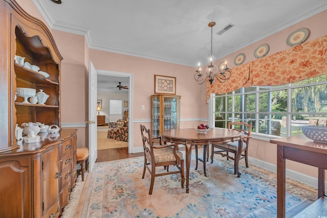 1259 Oatland Lake Rd, Pawleys Island, SC 29585 - dining area with ornamental molding, light wood-style flooring, a chandelier, a ceiling fan, and wainscoting