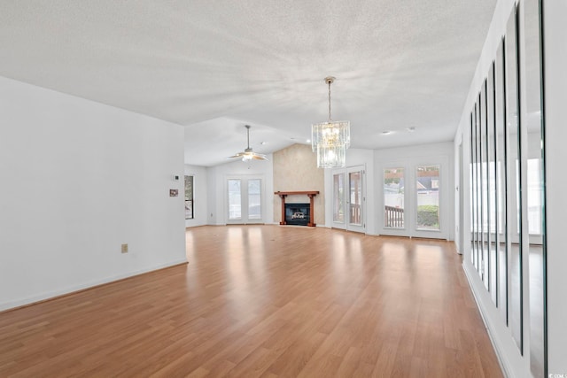 1468 Fox Hollow Way N, Myrtle Beach, SC 29582 - unfurnished living room featuring healthy amount of natural light, light wood-style flooring, a chandelier, a glass covered fireplace, and a textured ceiling