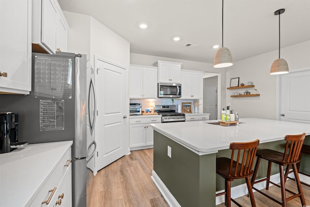 1523 Wood Stork Dr, Conway, SC 29526 - kitchen with stainless steel appliances, light wood-style floors, white cabinetry, a kitchen bar, and backsplash