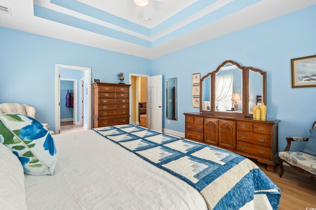 106 Cypress Creek Dr, Murrells Inlet, SC 29576 - bedroom featuring a spacious closet, light wood-type flooring, a tray ceiling, a closet, and a ceiling fan