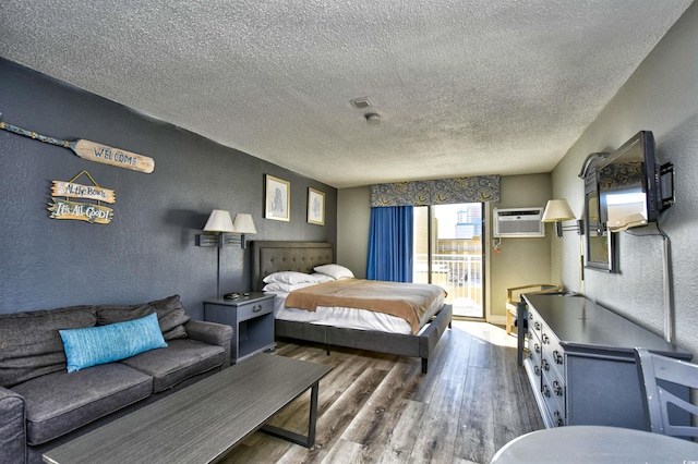 1207 S Ocean Blvd Unit 50809, Myrtle Beach, SC 29577 - bedroom featuring a textured wall, a textured ceiling, wood finished floors, a wall unit AC, and access to outside