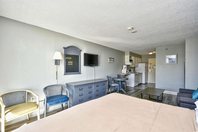 1207 S Ocean Blvd Unit 50809, Myrtle Beach, SC 29577 - bedroom featuring a textured ceiling, freestanding refrigerator, dark wood finished floors, and baseboards