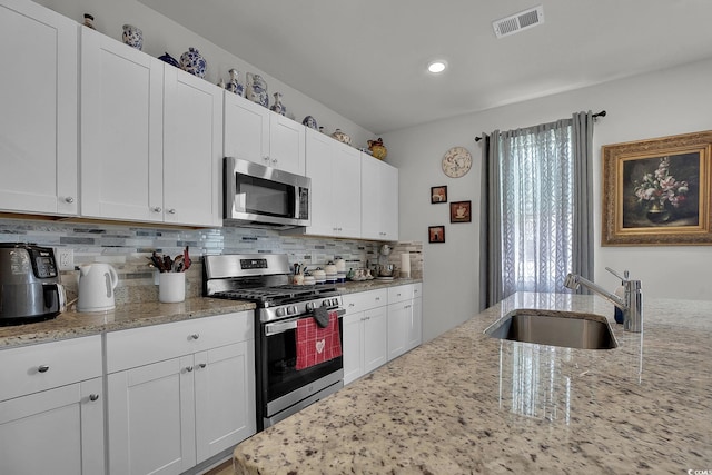 79 S Reindeer Rd, Surfside Beach, SC 29575 - kitchen with stainless steel appliances, a sink, tasteful backsplash, light stone counters, and white cabinetry