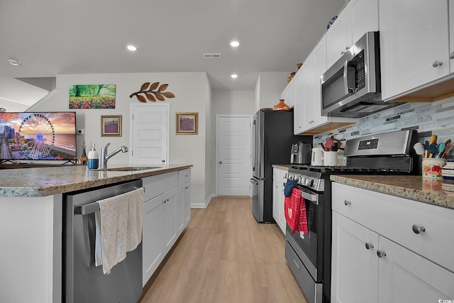 79 S Reindeer Rd, Surfside Beach, SC 29575 - kitchen with stainless steel appliances, a sink, white cabinets, light wood-style flooring, and recessed lighting