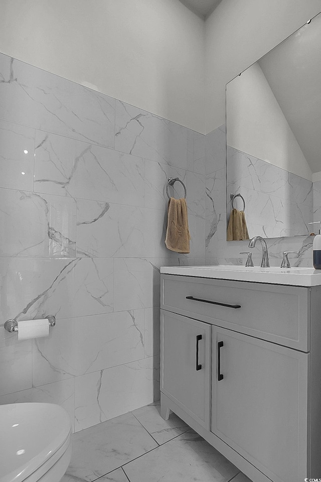 79 S Reindeer Rd, Surfside Beach, SC 29575 - bathroom with marble look tiles, vanity, tile walls, toilet, and a wainscoted wall