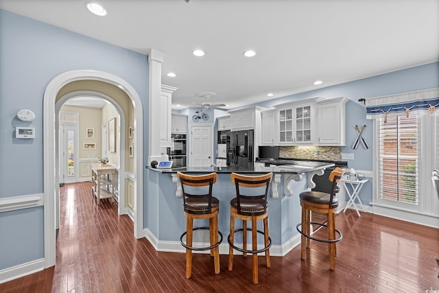 504 Sea Vista Ln, North Myrtle Beach, SC 29582 - kitchen with dark countertops, a breakfast bar, glass insert cabinets, black refrigerator with ice dispenser, and dark wood-style floors
