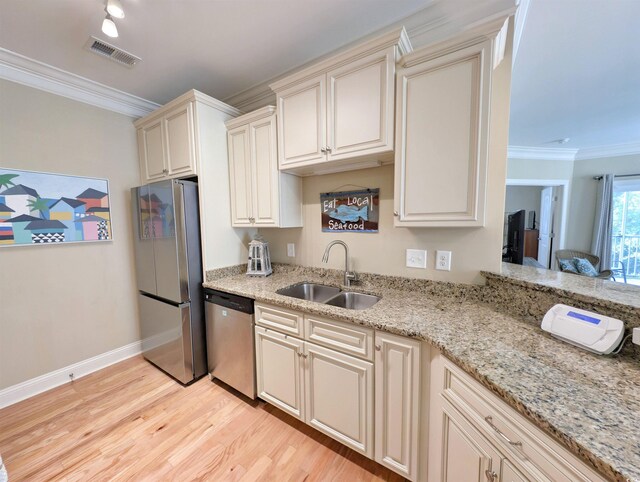 82 Mingo Dr Unit 2D, Pawleys Island, SC 29585 - kitchen featuring appliances with stainless steel finishes, a sink, light wood-type flooring, crown molding, and light stone counters