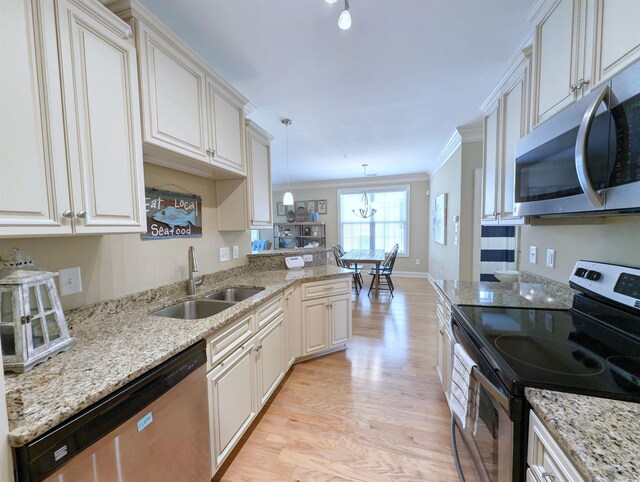 82 Mingo Dr Unit 2D, Pawleys Island, SC 29585 - kitchen featuring appliances with stainless steel finishes, a sink, light wood-style flooring, crown molding, and light stone counters