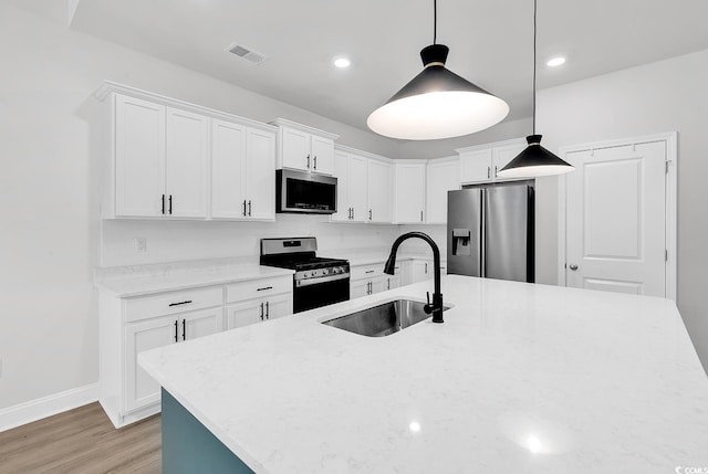 218 Calhoun Falls Dr, Myrtle Beach, SC 29579 - kitchen featuring stainless steel appliances, a sink, light wood-type flooring, white cabinetry, and a center island with sink