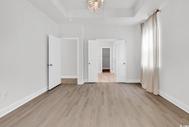 218 Calhoun Falls Dr, Myrtle Beach, SC 29579 - unfurnished bedroom with a raised ceiling, a chandelier, light wood finished floors, and baseboards