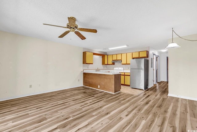 3700 Golf Colony Ln Unit 25G, Little River, SC 29566 - kitchen featuring freestanding refrigerator, a peninsula, light countertops, under cabinet range hood, and white electric range