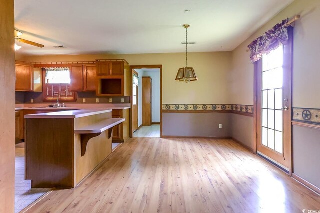3150 Dusty Rd, Loris, SC 29569 - kitchen with brown cabinetry, light wood-style flooring, decorative light fixtures, a center island, and a kitchen breakfast bar